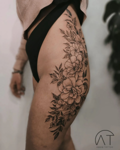 duży tatuaż damski z motywem kwiatów na udzie