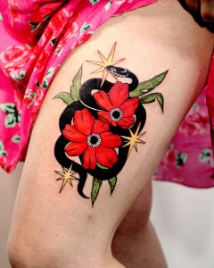 kolorowy tatuaż damski na udzie - wąż w czerwonych kwiatach