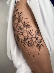 tatuaż roślinny damski na udzie - kwiaty