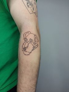 tatuaż na ramieniu z konturem głowy psa w otoczeniu kwiatów, popularne tatuaże zwierzęta 2024