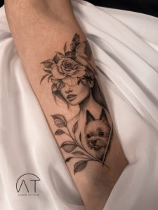 Sztuka tatuażu kwiatowego na ramieniu, z wizerunkiem kobiety otoczonej przez kwiaty i liście, popularne tatuaże kwiaty w 2024 roku