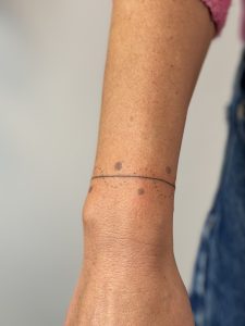 Minimalistyczny tatuaż handpoke przedstawiający delikatną gałązkę