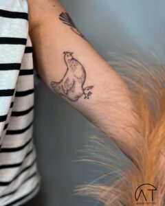 Minimalistyczny tatuaż kury na przedramieniu – delikatny tatuaż pupila