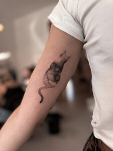 Realistyczny tatuaż kota na przedramieniu – delikatny portret kota w czerni