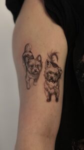 Tatuaż dwóch psów w stylu realistycznym – portret pupili na ramieniu