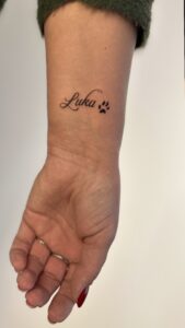 Mały tatuaż łapki z imieniem psa – subtelny tatuaż pupila na nadgarstku