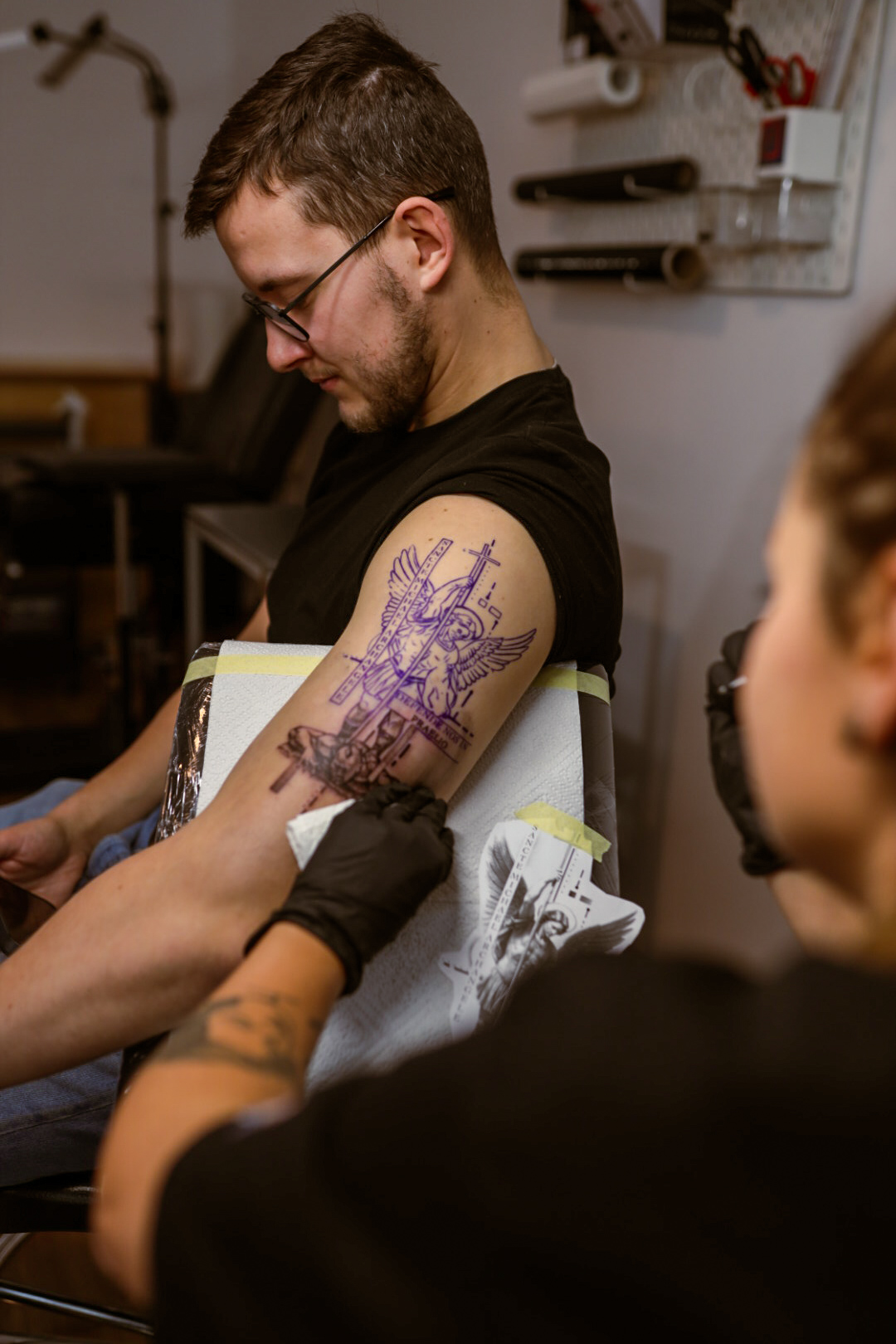 Przenoszenie fioletowego wzoru tatuażu na ramię klienta przed rozpoczęciem sesji