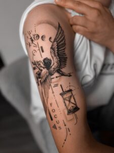 Tatuaż konceptualny z orłem, wagą, napisami i geometrycznymi symbolami na ramieniu