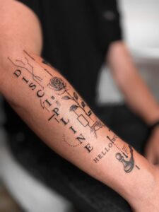 Tatuaż konceptualny z różą, napisami i graficznymi detalami na przedramieniu