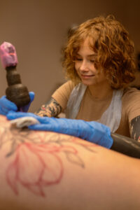 Tatuatorka wykonuje tatuaż podczas sesji w studiu Szelma Tattoo
